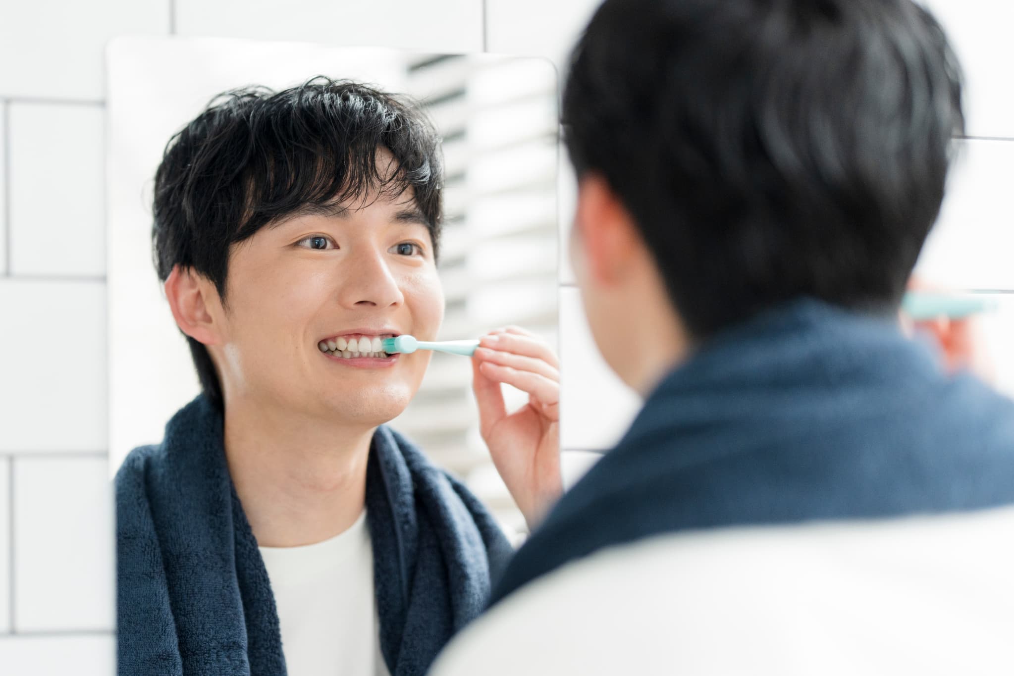 鏡を見ながら丁寧に歯みがきをする男性